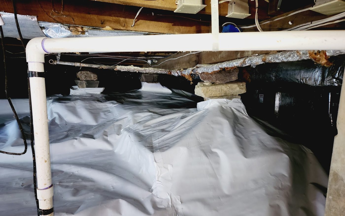 Crawl space mid-installation, exposed dirt and rock, before vapour barrier is completed