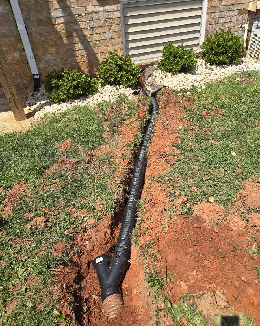 Finished french drain line restored with mulch and landscaping along a foundation
