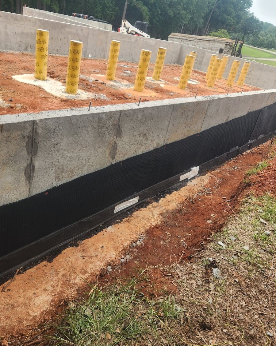 New-construction foundation wall with waterproofing membrane and drainage board before backfill